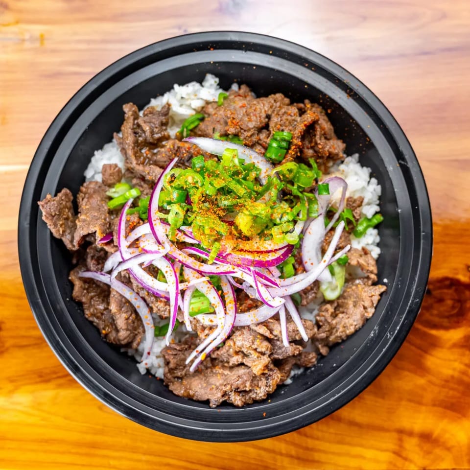 Pokefit's bulgogi bowl with white rice, sliced beef, red onions, green onions, and spices.